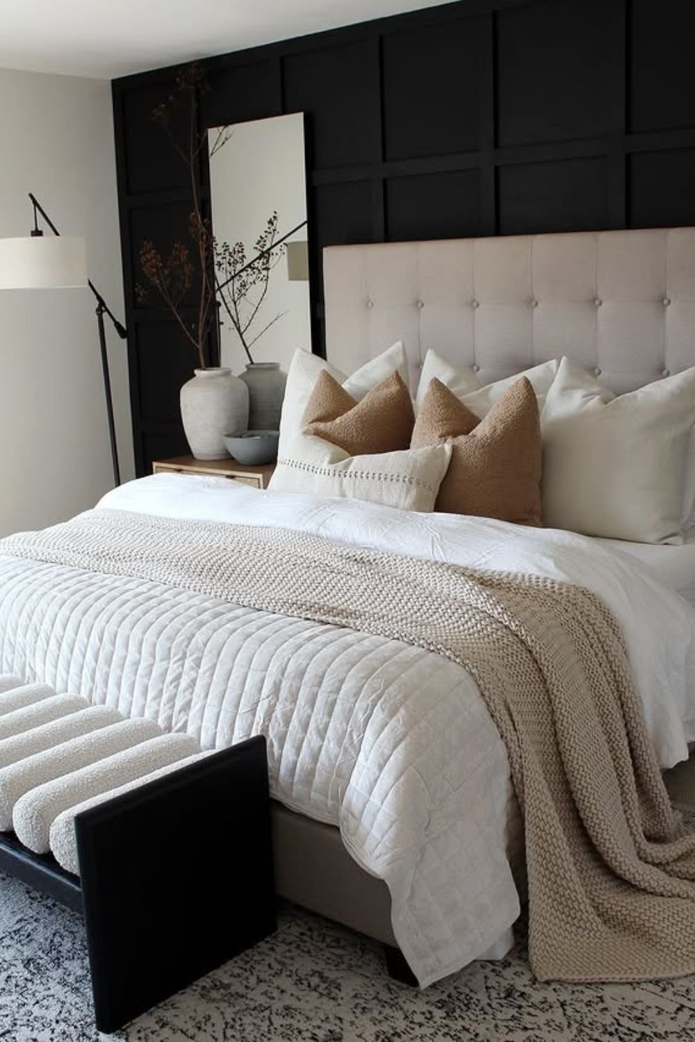 Dark paneled wall framing an upholstered headboard with neutral bedding
