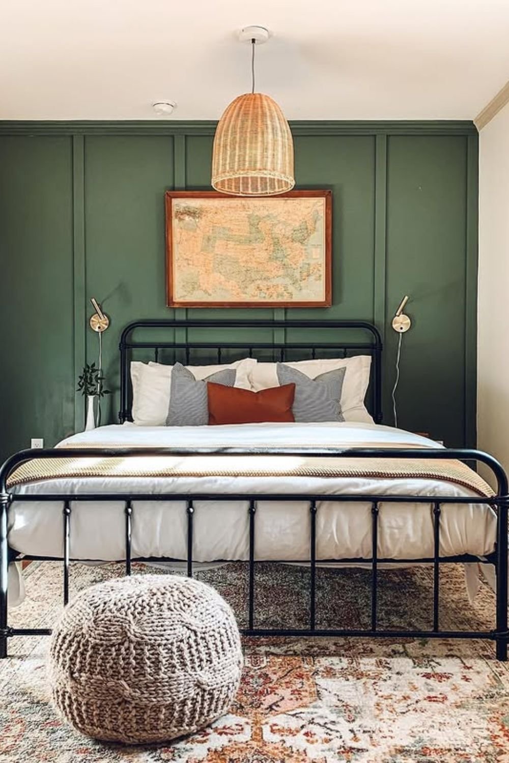 Rich green vertical paneling behind a black metal bed