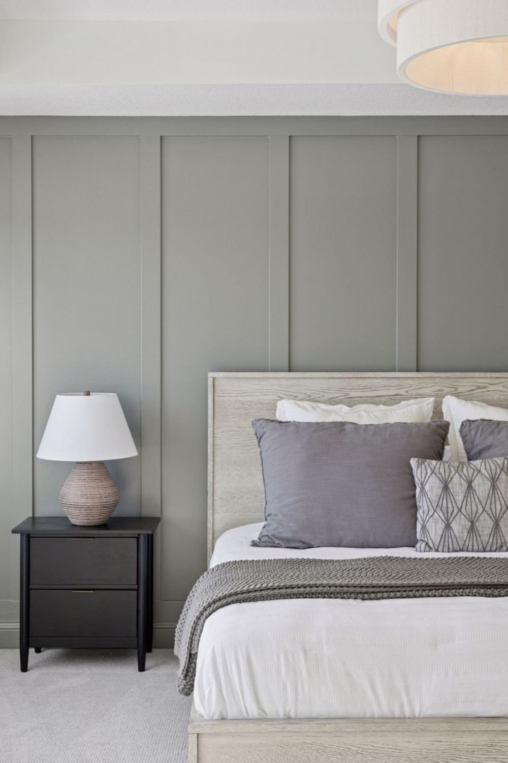 Warm greige panel wall behind a bed with soft neutral bedding