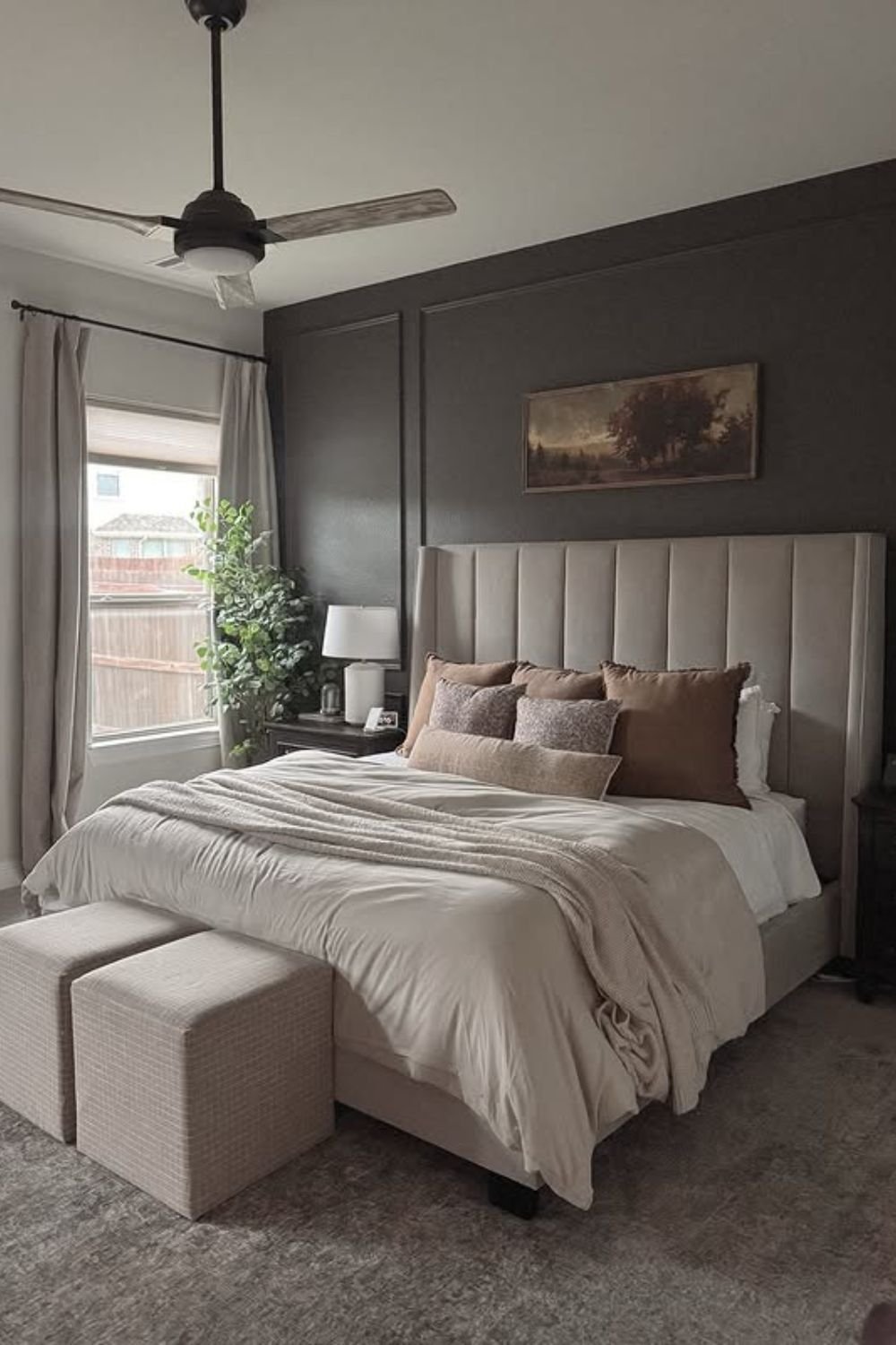 Deep charcoal panel wall behind an upholstered headboard with neutral bedding