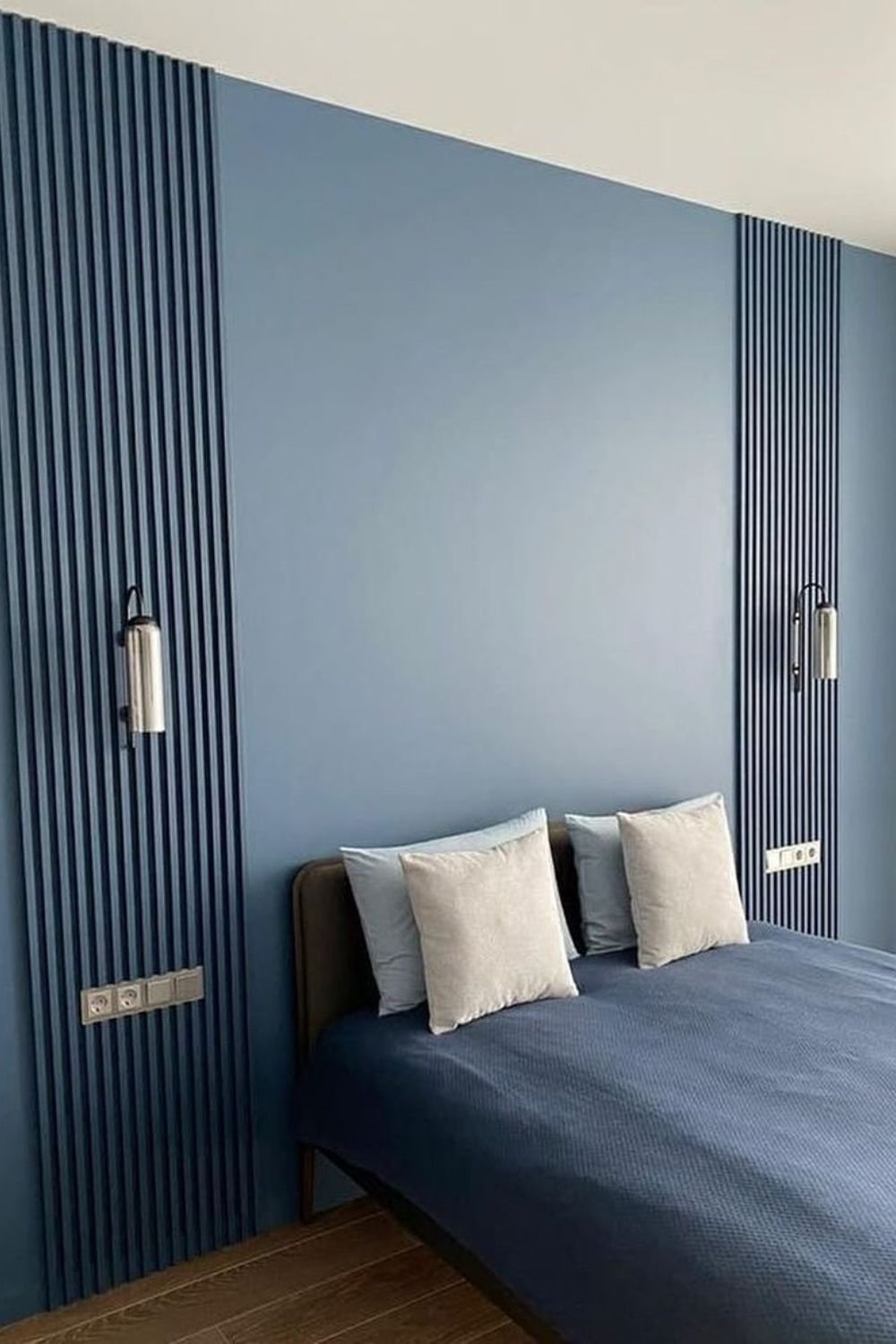 Muted blue vertical slats framing a bed with raised panel texture