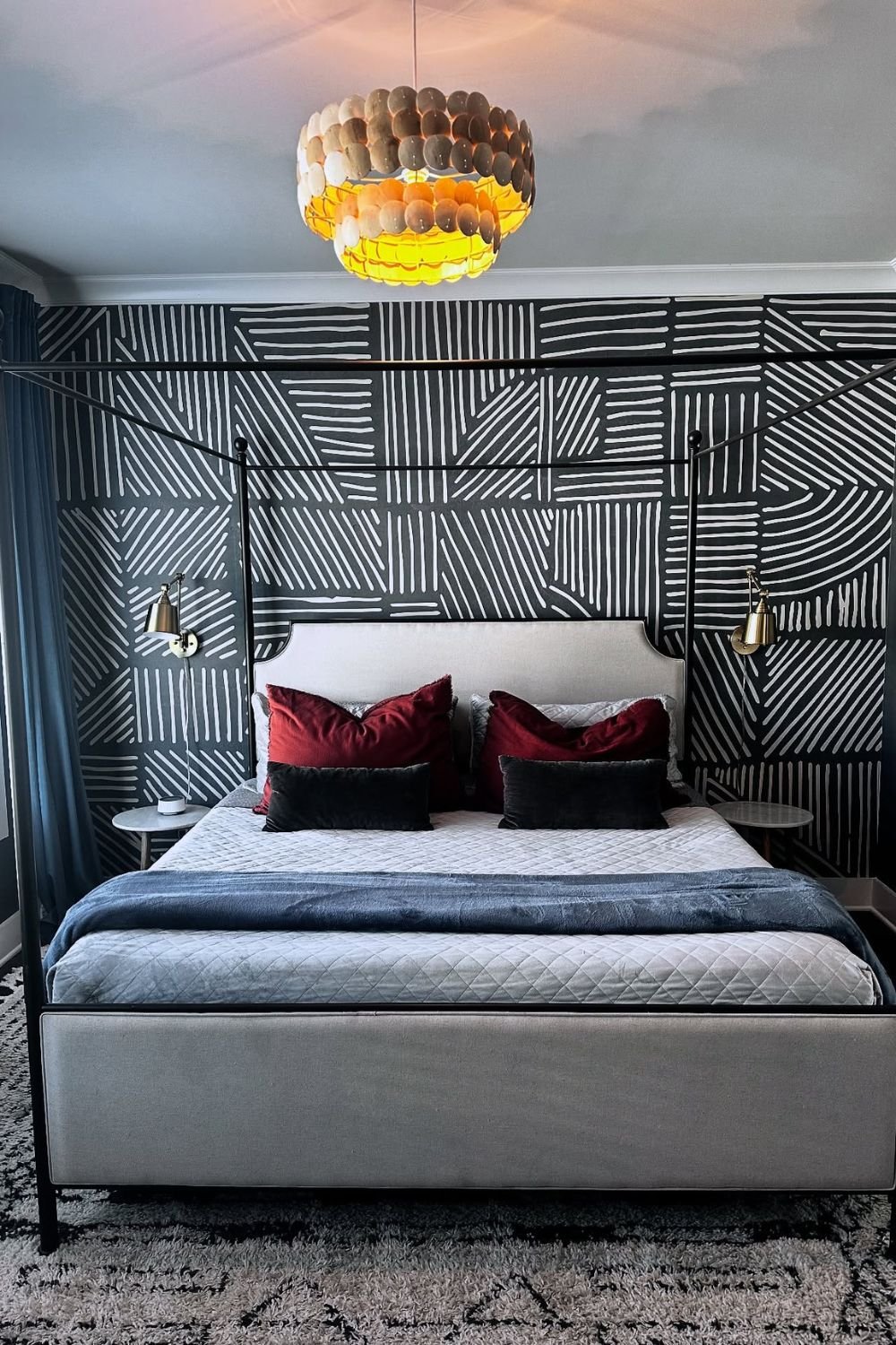 Black-and-white geometric wallpaper behind a simple bed