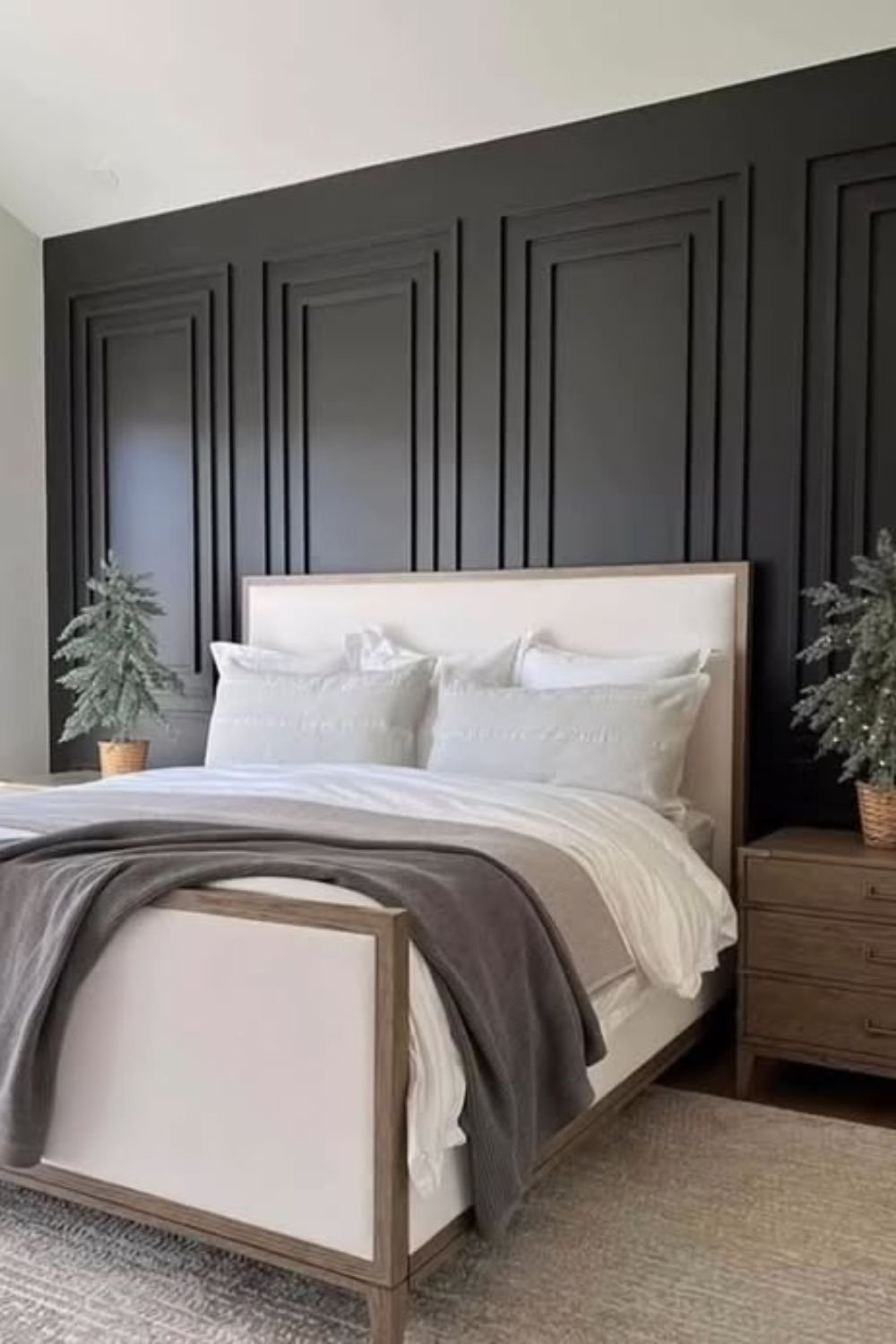 Deep black feature wall behind a light bed frame with natural light