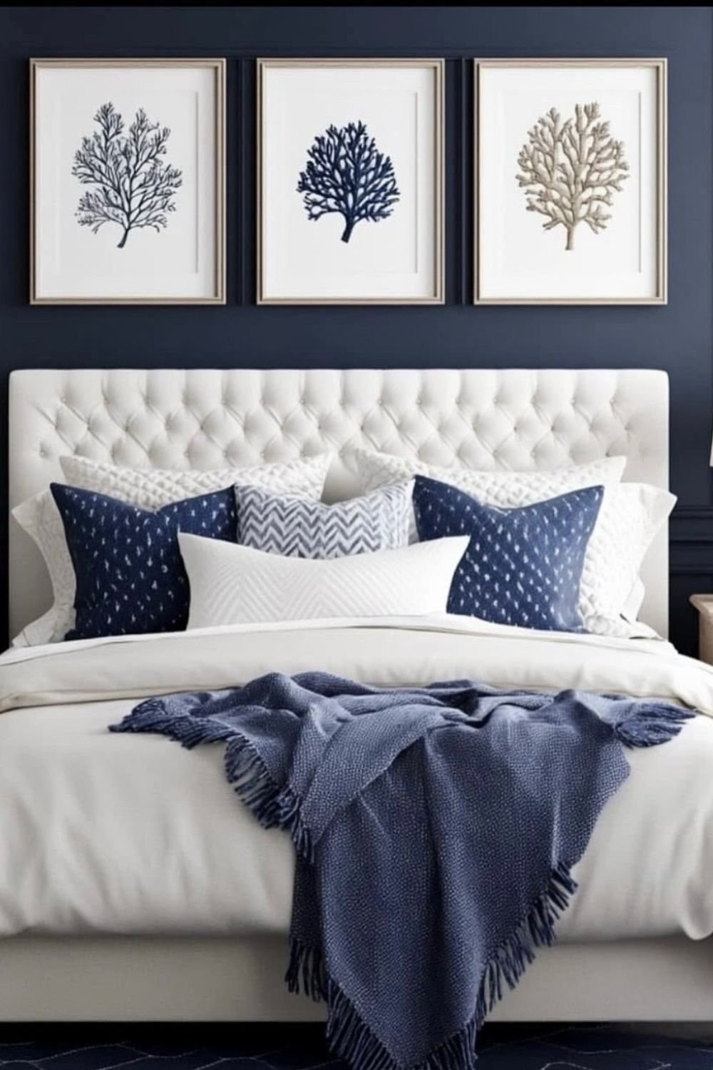 Deep navy paneled wall with framed art and upholstered headboard