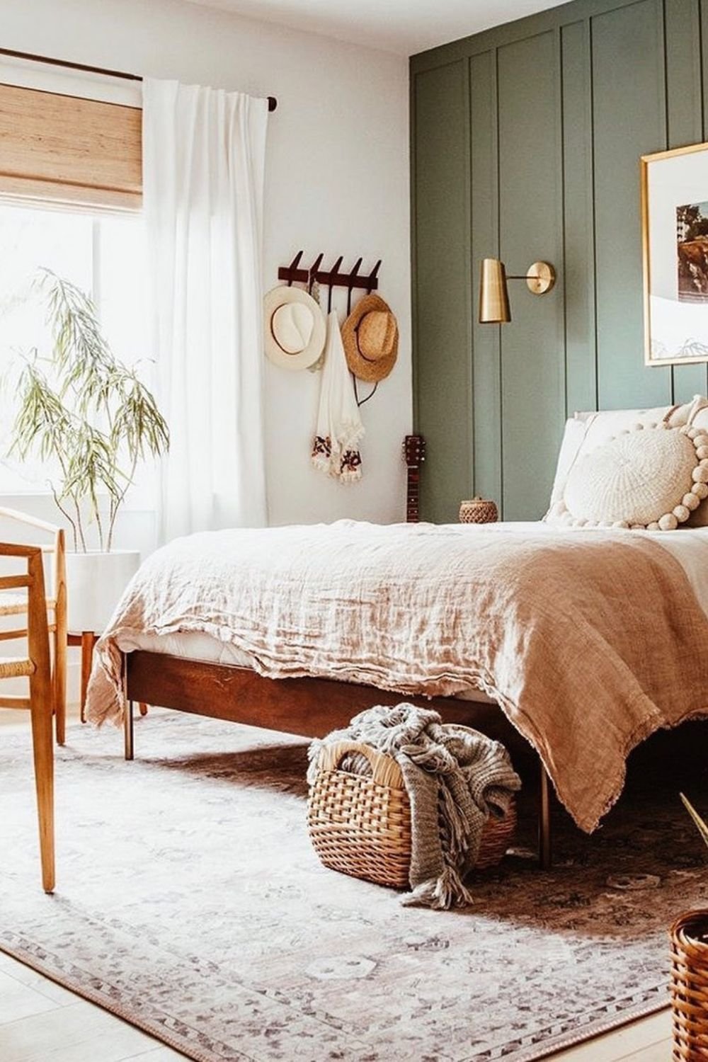 Muted sage green paneling behind a bed with woven accents and natural textures