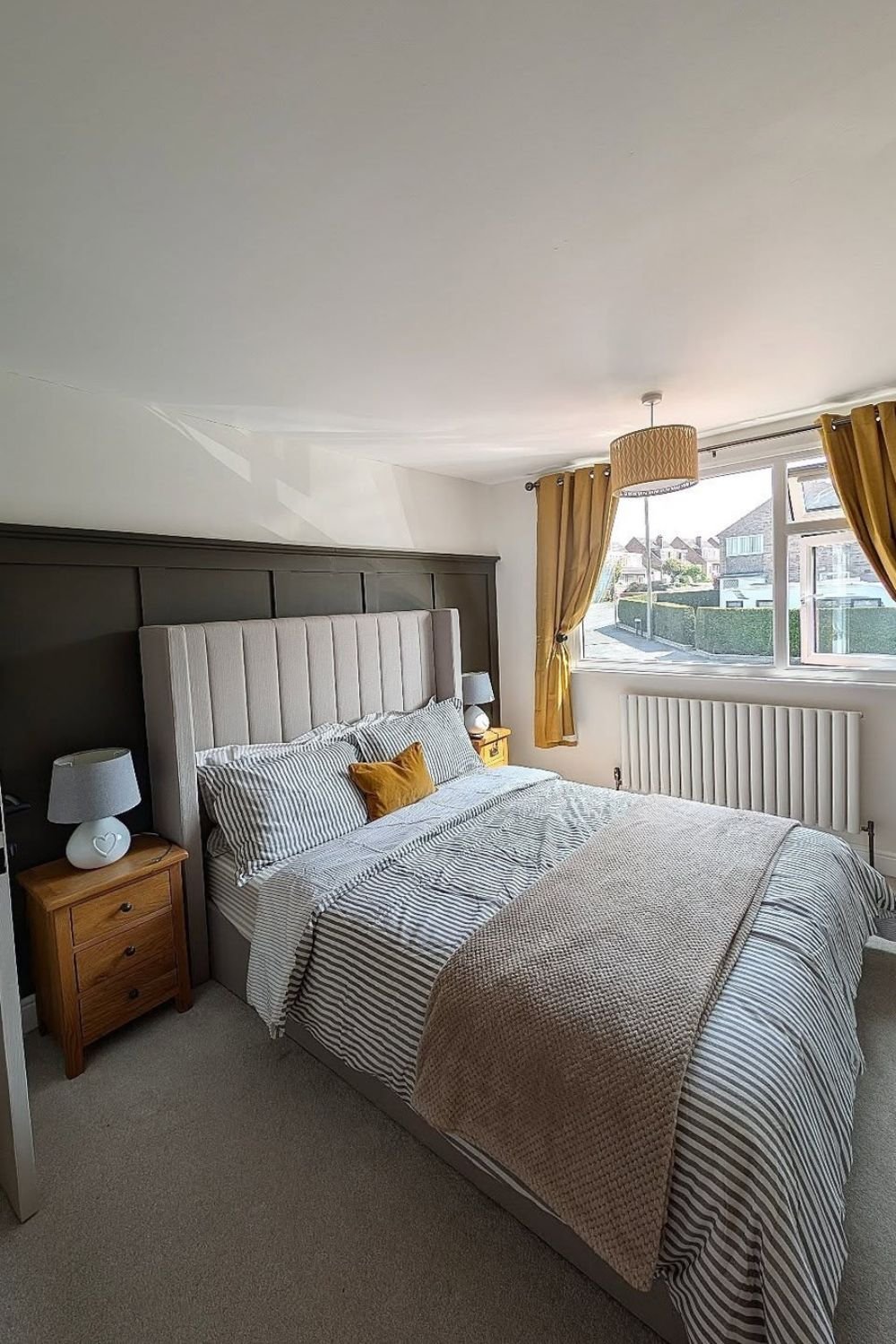 Taupe paneling behind a bed in a small bedroom with natural light
