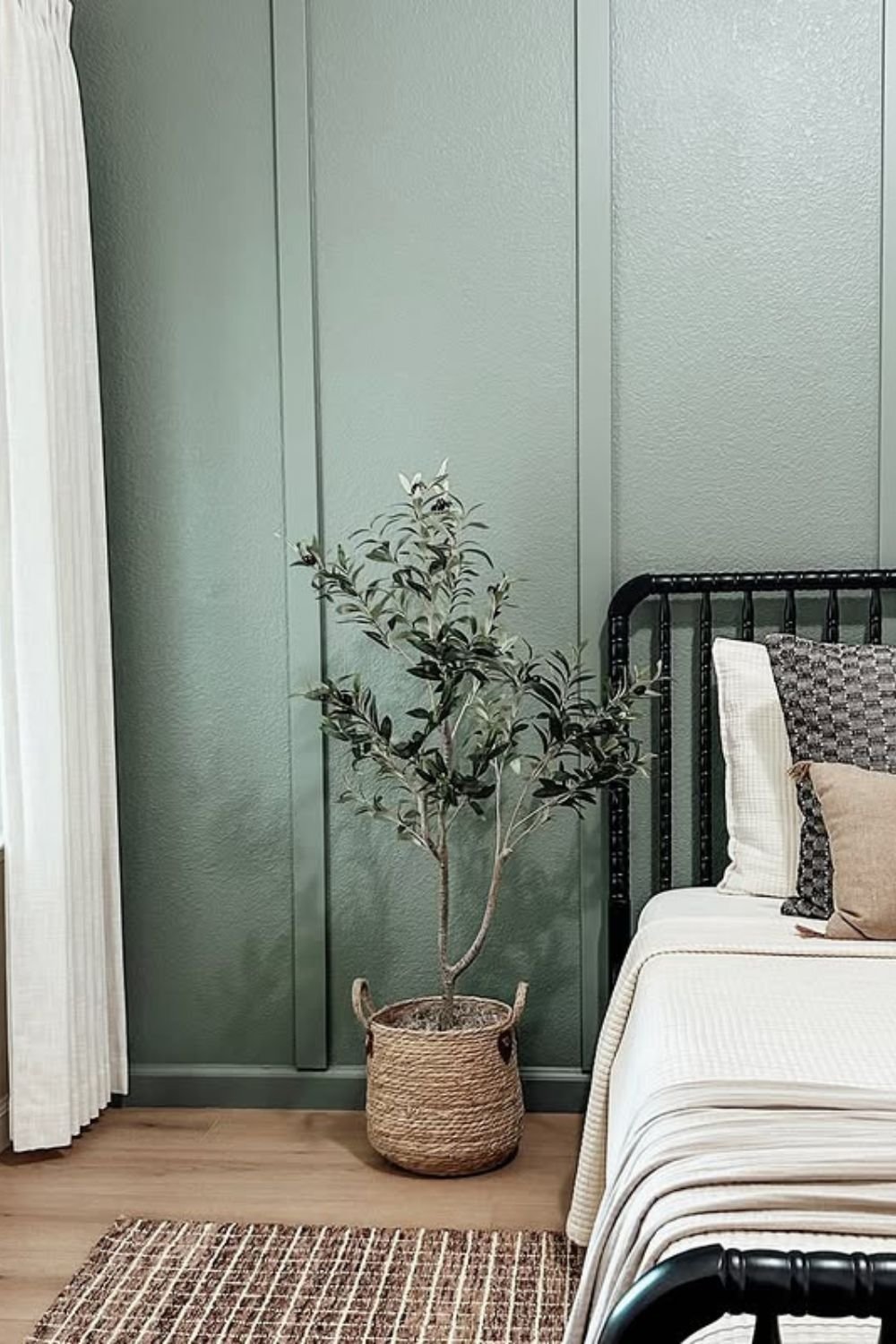 Sage green vertical paneling behind a bed with plants and baskets