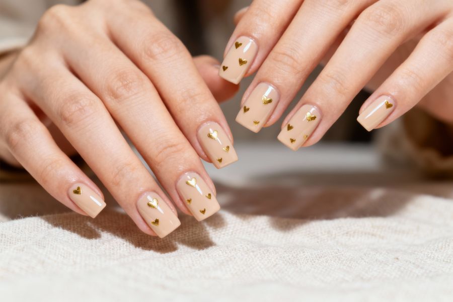 Beige square nails with delicate gold heart accents for a chic, romantic touch.