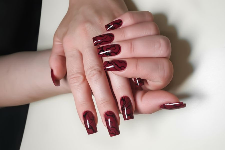 Crimson square nails featuring glossy black marble vein accents for a bold, elegant look.