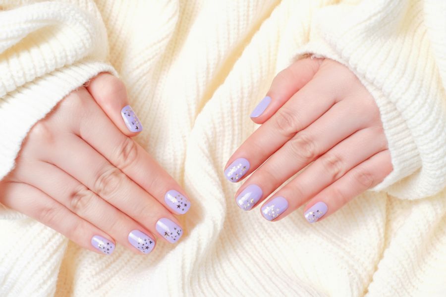 Pastel lilac square nails decorated with tiny silver and gold star accents.