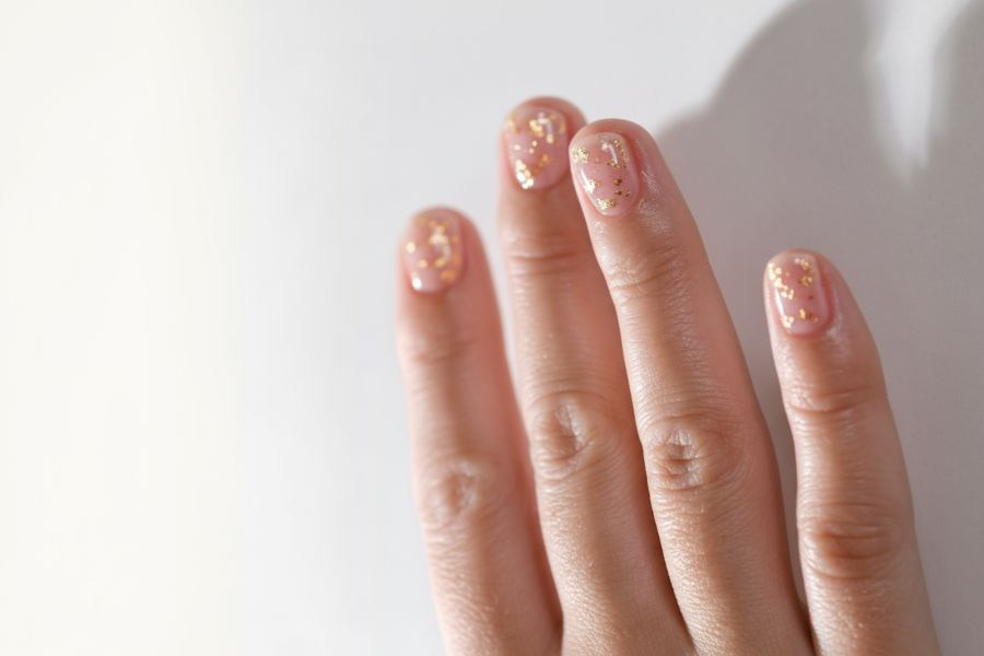 Sheer pink square nails with scattered tiny gold flakes for a soft and elegant finish.