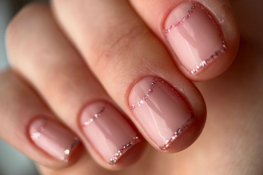 Soft pink square nails with delicate glittery tips for a subtle, elegant finish.