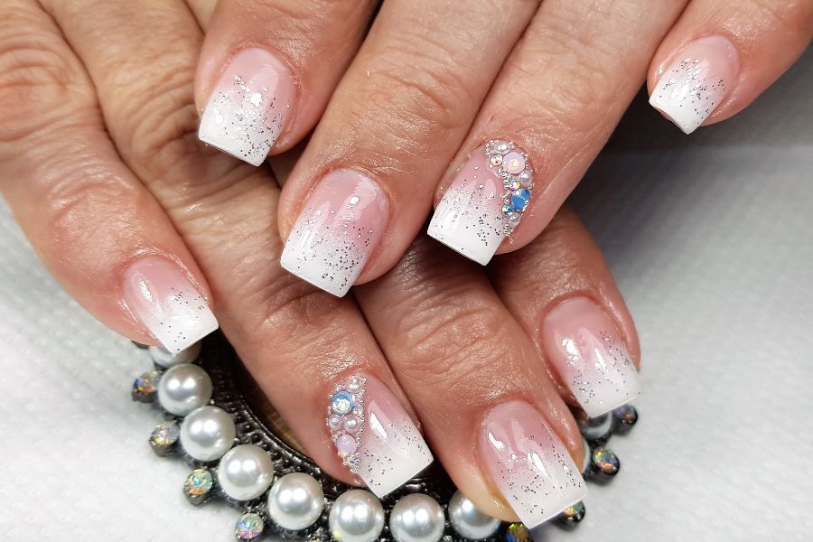 Elegant white square nails with silver glitter gradient and 3D pearl and rhinestone embellishments.