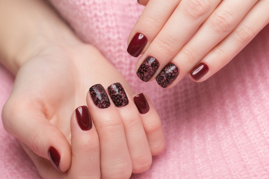 Wine red square nails featuring intricate black lace patterns for a bold, elegant look.