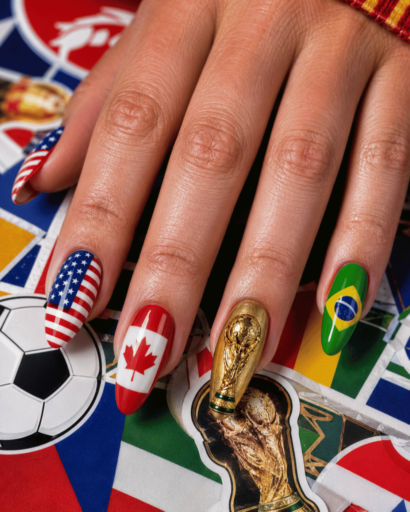 World Cup trophy nails featuring country flag nail art and a gold championship trophy accent nail.