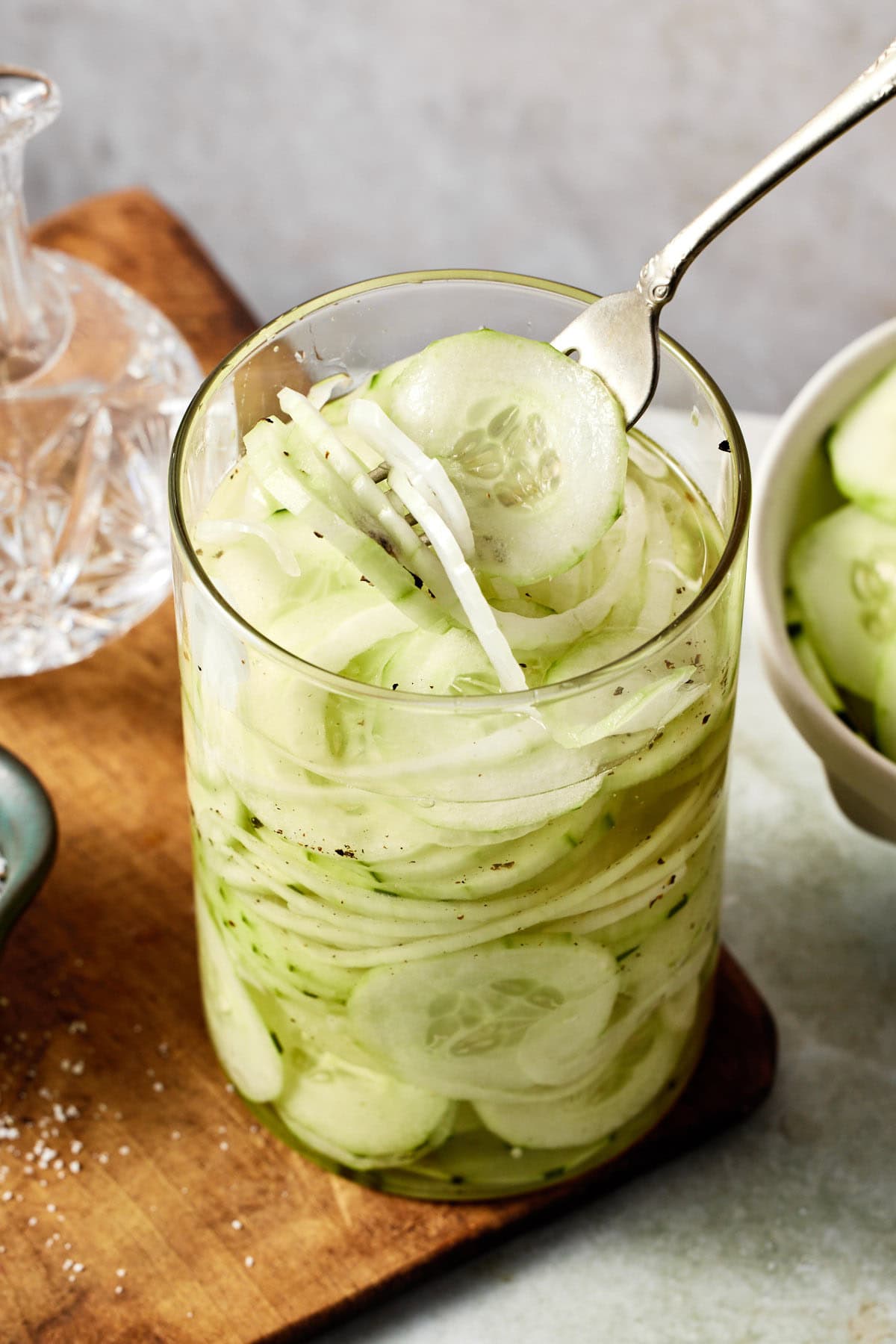 A fork lifting a bite of cucumber vinegar salad out of a glass jar with a fork.