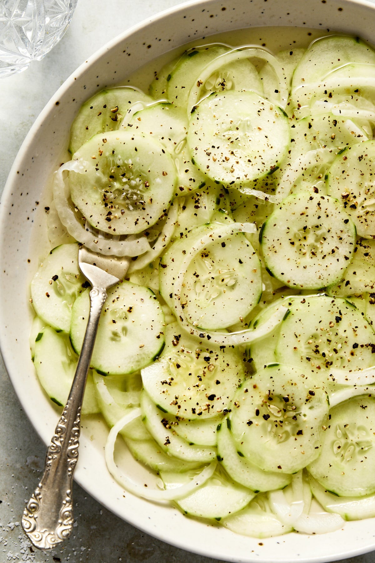 A close up photo of cucumber vinegar salad in a bowl with a fork.