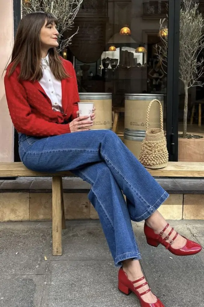 Fashionable fall outfit featuring red textured jacket, white shirt, high-waisted jeans, and strapped red shoes.