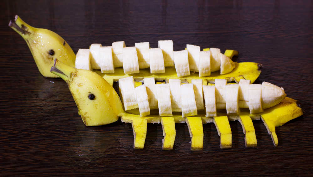 Bananas sliced and sitting on banana skins in the shape of ducks.