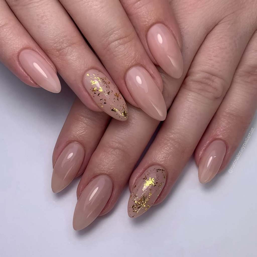 classy almond shaped beige nails with cute gold flake designs
