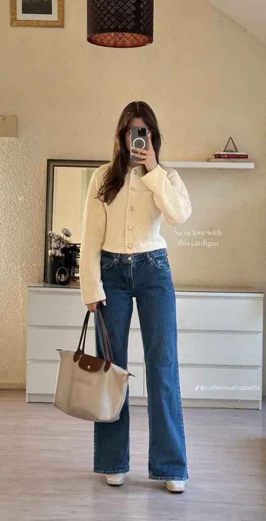 Woman wearing a cropped cream cardigan with wide-leg jeans and a neutral tote bag.