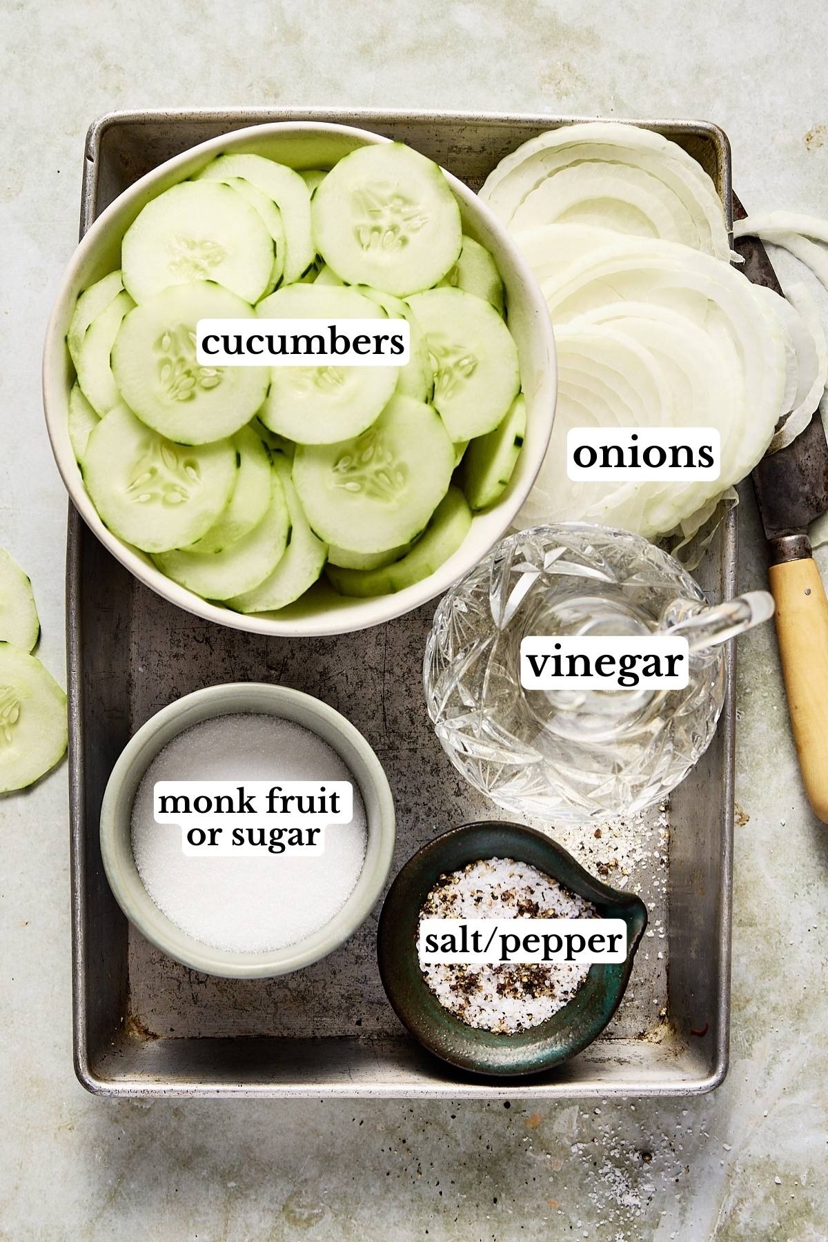 Cucumber vinegar salad ingredients labeled in small bowls.