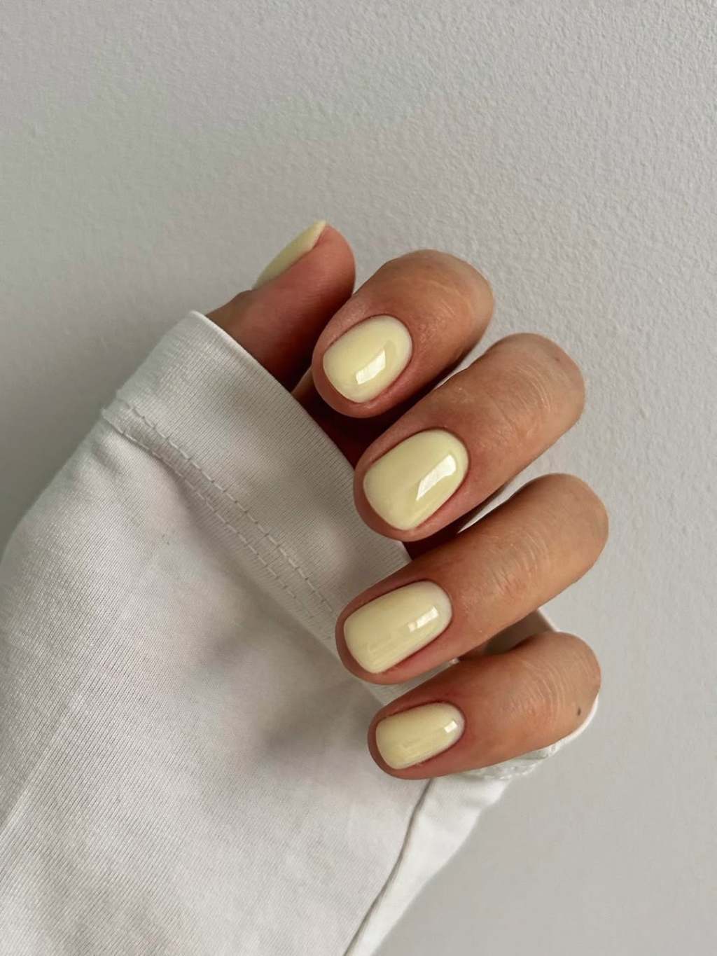 Short rounded simple nails in a creamy butter yellow milky finish
