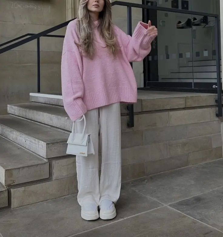 Fall outfit with oversized pink sweater, wide-leg white pants, chunky white sneakers, and small structured handbag.