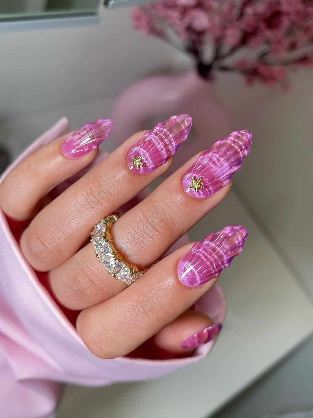 textured pink 3d seashell cat eye nails with gold starfish charms and diamond ring.