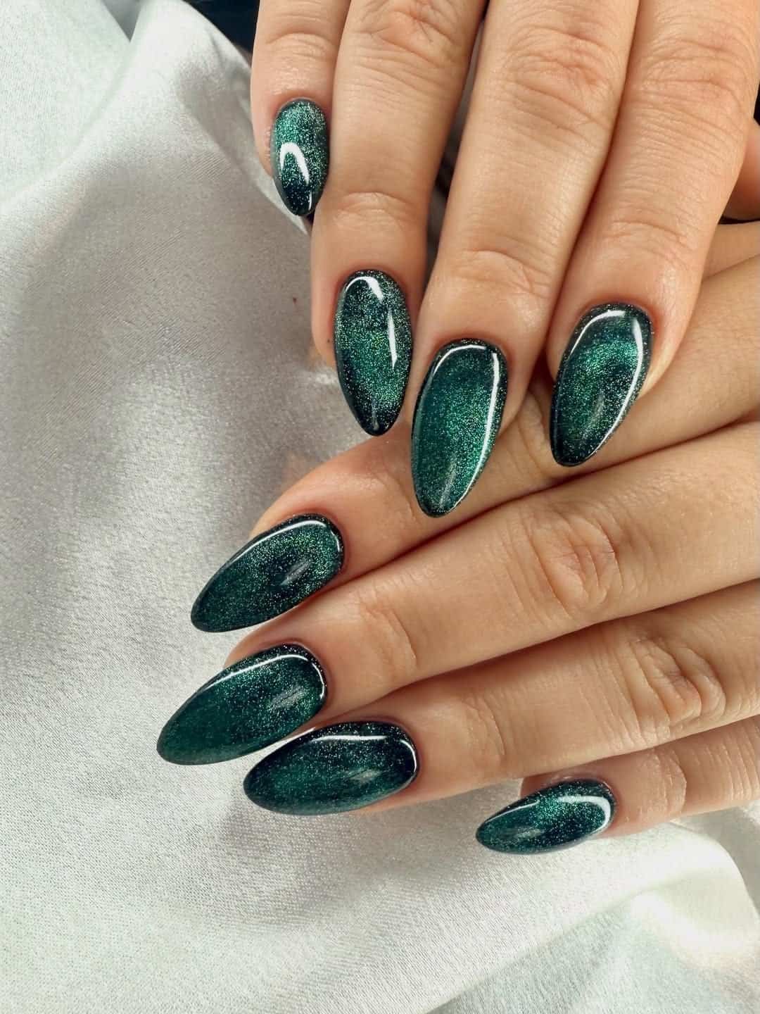 dark emerald green cat eye summer nails with a glittery magnetic effect on almond tips.