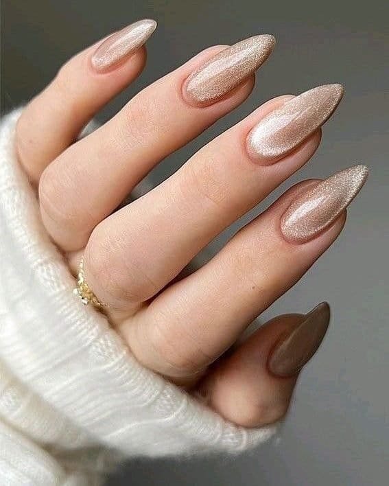 shimmering champagne gold cat eye summer nails on long almond shaped fingers with white sweater.