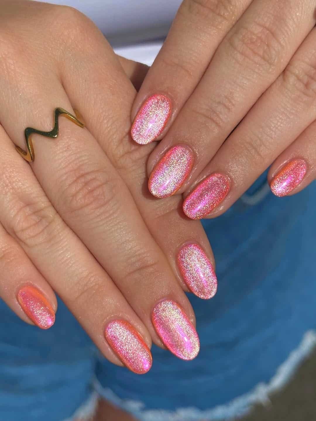 bright coral pink cat eye summer nails with a glittery magnetic shimmer on short ovals.