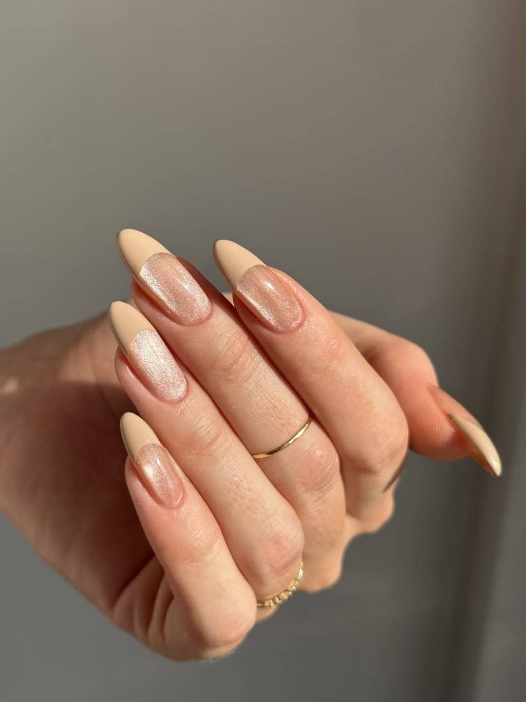 nude cat eye nails with matte tan french tips on long almond shaped fingers.