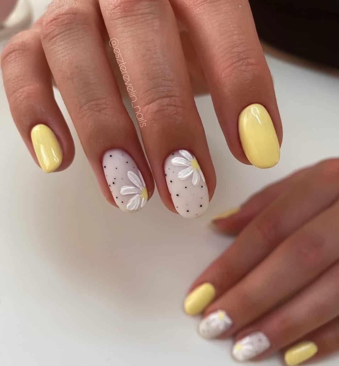 glossy pale yellow oval nails featuring textured white daisy art and black polka dot accents