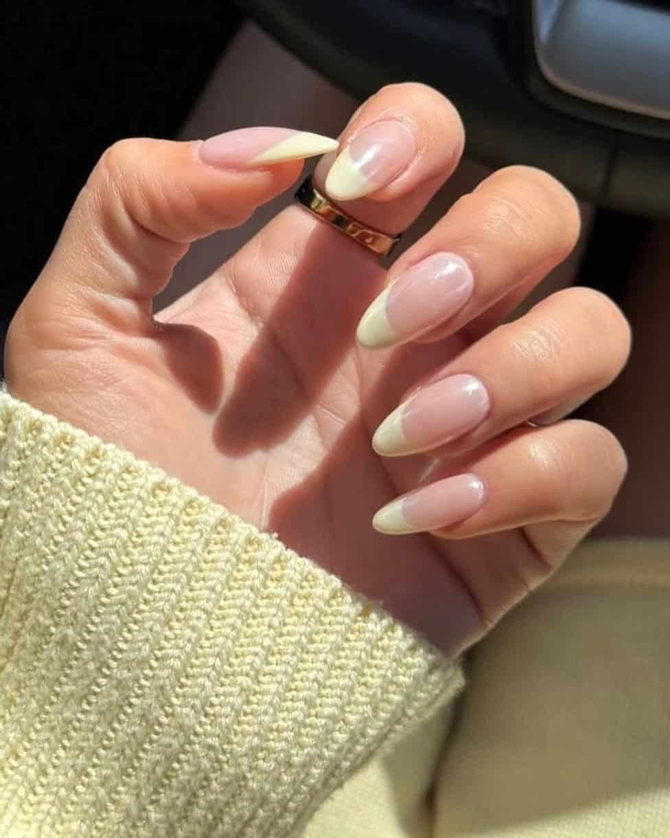 classic yellow french tip manicure on long almond shaped nails with a gold ring