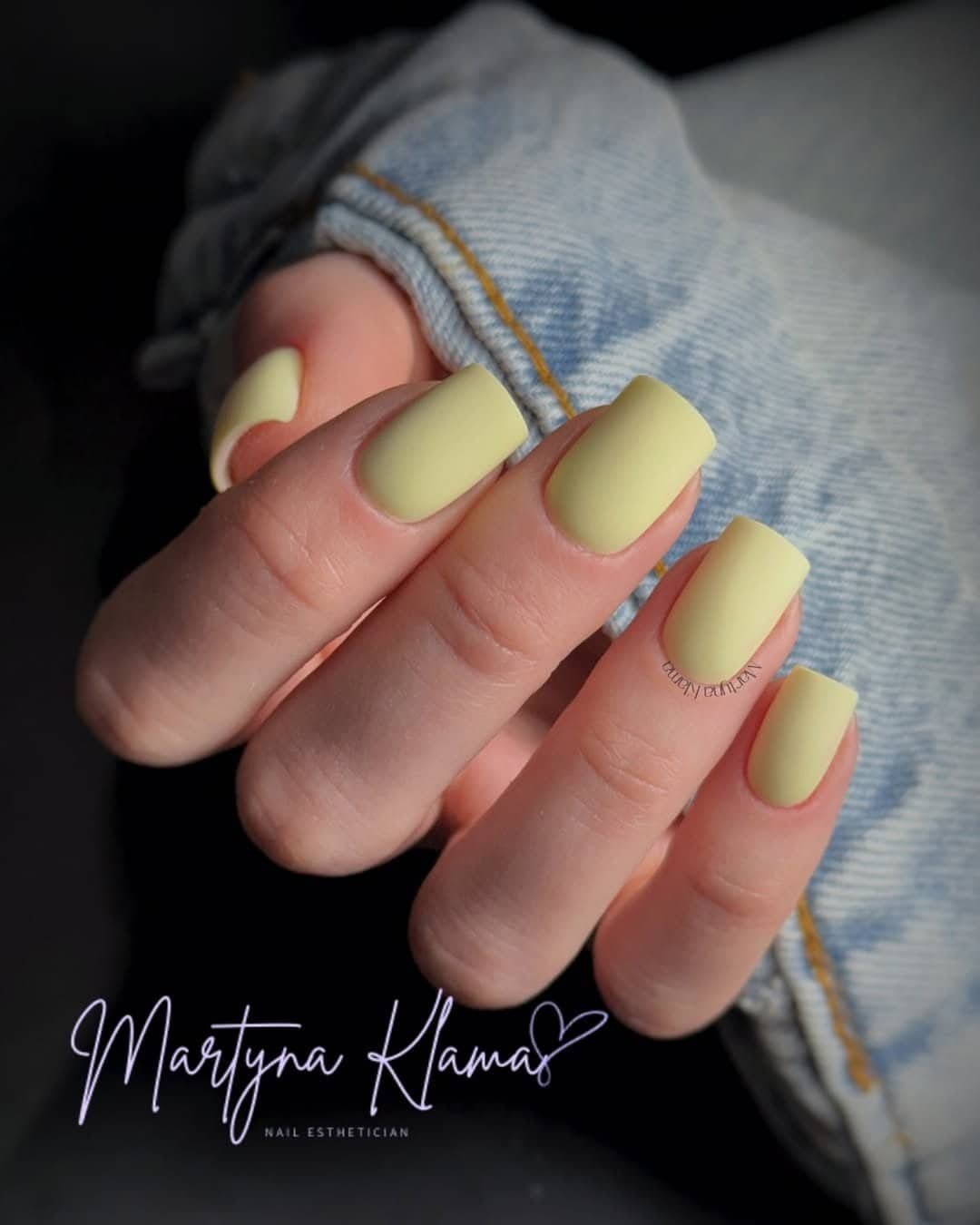 matte pastel yellow square manicure on a hand resting against a light denim jacket