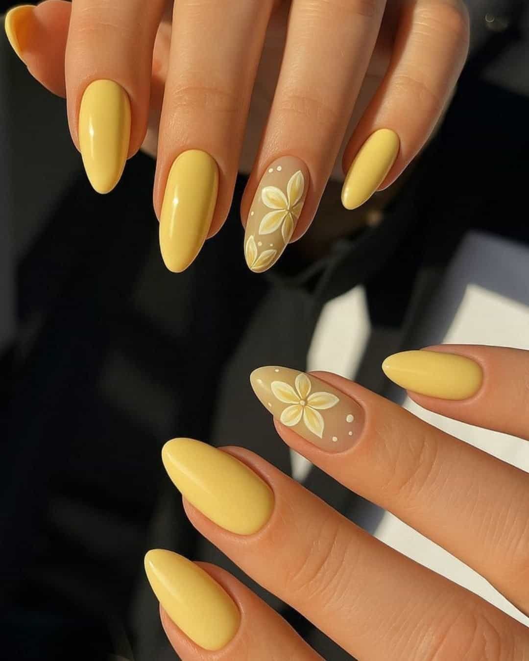 glossy pastel yellow almond nails featuring hand painted white and yellow floral accent art
